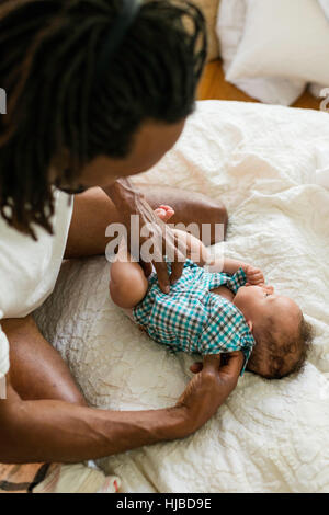 Vater putzt sich Baby im Bett Stockfoto