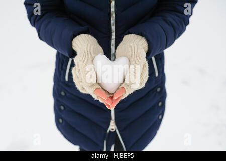 Frau in weißen Handschuhe hält einen verschneiten Herz Stockfoto