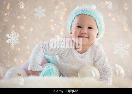 Niedliche Baby Mädchen posiert und lächelnd mit Weihnachten Snowflake Ornamente und Kugeln Stockfoto