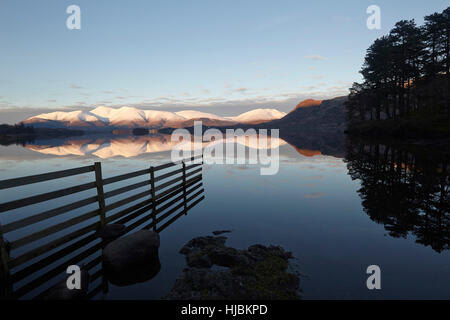 Abendlicht der Sonne fängt die schneebedeckten Hänge des Skiddaw und Blencathra spiegelt sich in Derwent Wasser Seenplatte, Cumbria Stockfoto