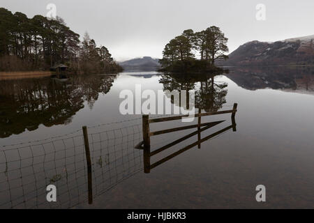 Berge, ein Zaun und Bäume in der ruhigen Oberfläche des Derwent Water wider, Keswick, Cumbria, Lake District, England Großbritannien Stockfoto