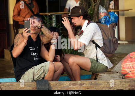 Westliche Touristen nehmen Fotos von überfluteten Straßen und Flüsse in Hoi an, Vietnam während Massen beobachten und abwarten Stockfoto