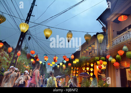 Globale Touristen nehmen Sie Fotos und Selfies auf Hoi an einer Straße mit bunten Orange, blau, gelbe Laternen oben im Shopping District Stockfoto