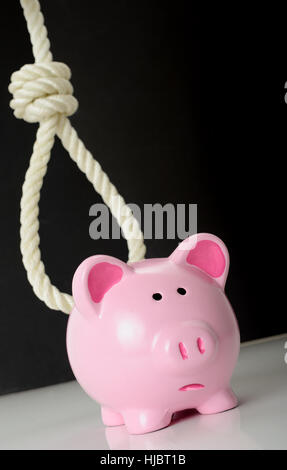 Konzept der Finanzprobleme ein Sparschwein mit einer sich abzeichnenden Schlinge im Hintergrund Stockfoto