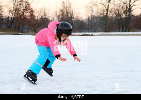 Kind Mädchen nach einem Sturz im verschneiten Park während der Winterferien auf Eis liegen. Stockfoto