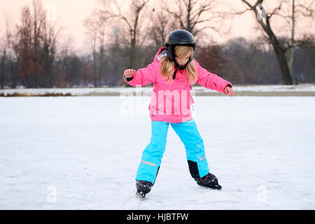 Glückliche kleine Mädchen Eislaufen im Winter im Freien, Schutzhelm tragen Stockfoto