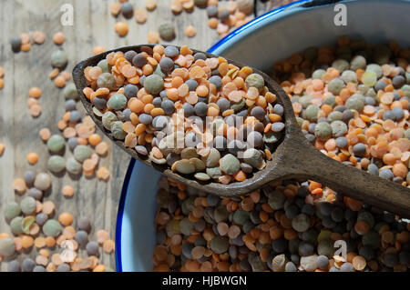 Linsen in ein weißes Metall Schüssel und alten Holzlöffel Stockfoto