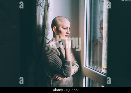 Porträt der jungen Frau mit rasierten Kopf, Blick durch Fenster Stockfoto