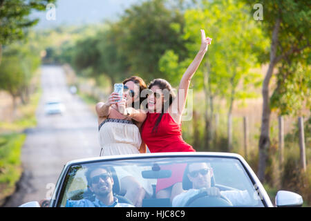 Zwei junge Freundinnen nehmen Selfie während der Fahrt auf der Landstraße im Cabrio, Mallorca, Spanien Stockfoto