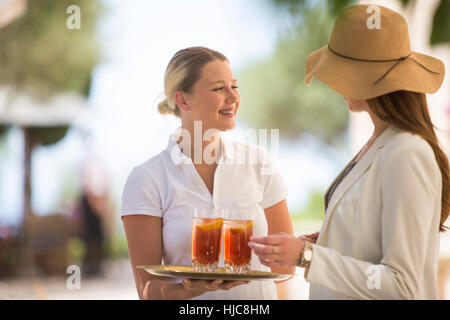 Boutique-Hotel Kellnerin freundliche junge Frau mit Getränken, Mallorca, Spanien Stockfoto