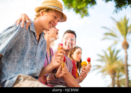 Vier Erwachsene Freunde lachen und essen Eis Creme Zapfen, Mallorca, Spanien Stockfoto