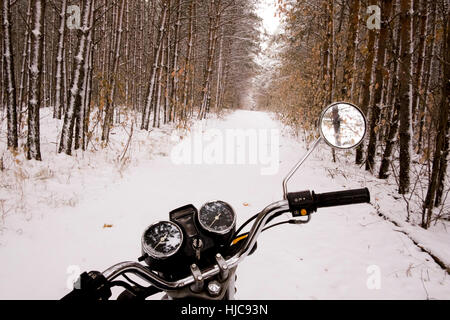 Motorrad geparkt im verschneiten Wald Stockfoto