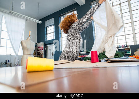 Reife weibliche Mode-Designer Textil durch Workshoptisch hochhalten Stockfoto