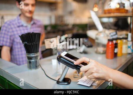 Schuss der Kundin mit Smartphone kontaktloses Bezahlen in Café beschnitten Stockfoto