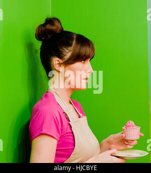 Junge Frauen Baker Holding Tasse Kuchen essen schuldig fühlen Stockfoto