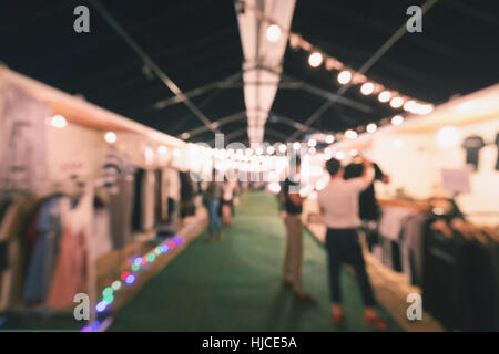 Verschwommene Szene von Menschen zu Fuß und Produktauswahl in Outdoor-Straßenmarkt in der Nacht. Stockfoto