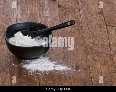 Maismehl in Schüssel geben. Rustikale Holz Hintergrund. Stockfoto