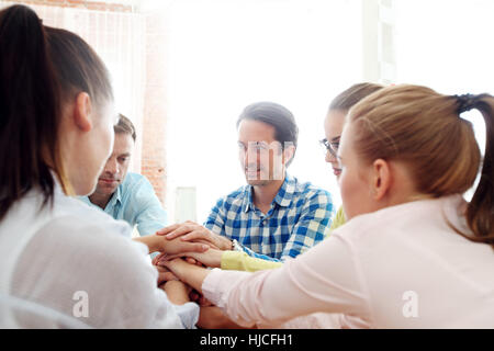 Kollegen, die Hände am Bürotisch stapeln Stockfoto