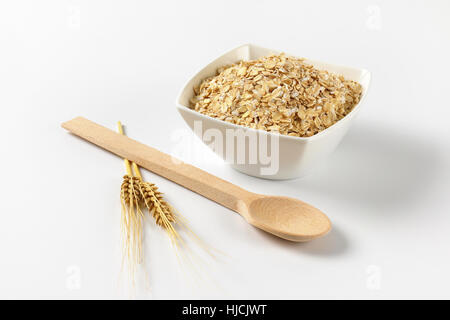 Schüssel mit Haferflocken auf Wollweiß Hintergrund mit Schatten Stockfoto