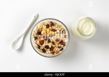 Schüssel mit Haferflocken und ein Glas weißen Joghurt auf Wollweiß Hintergrund mit Schatten Stockfoto