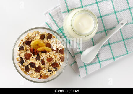 Schüssel mit Haferflocken und ein Glas weißen Joghurt auf kariertes Geschirrtuch Stockfoto