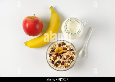 Schüssel mit Haferflocken, Krug mit Milch und Obst auf Wollweiß Hintergrund mit Schatten Stockfoto