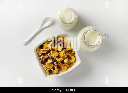 Schüssel mit Haferflocken mit Milch und Joghurt auf Wollweiß Hintergrund mit Schatten Glas Krug Stockfoto