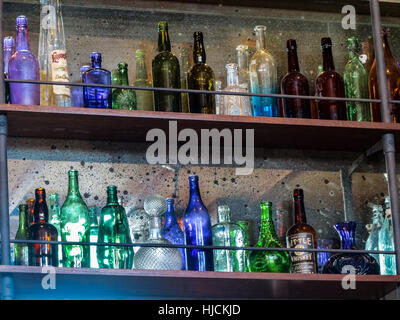 Viele verschiedene farbige Glasflaschen in den Regalen. Stockfoto