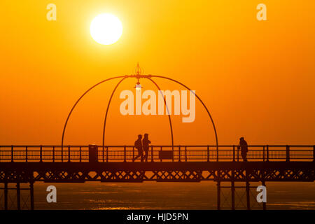 Sonnenuntergang über Southport, Merseyside. Großbritannien Wetter: 23. Januar 2017.  Als die Sonne schließlich bricht durch den eiskalten Nebel über Southport löschen, Menschen genießen den letzten von der Sonne durch einen Spaziergang hinunter Southport des berühmten viktorianischen Pier. Bildnachweis: Cernan Elias/Alamy Live-Nachrichten Stockfoto