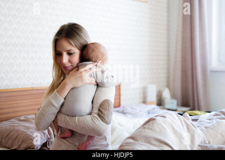 Schöne junge Mutter mit Baby Sohn in die Arme Stockfoto