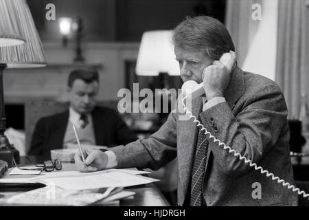 Präsident Carter am Telefon am Abend vor seiner Amtseinführung 1977 mit Staatssicherheit Berater Zbigniew Brezinski an seiner Seite. Stockfoto