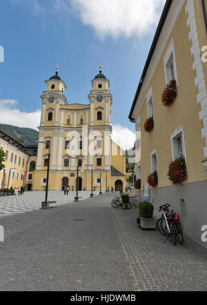 MONDSEE, Österreich - 10. September 2015: Unbekannte Menschen gehen vor St. Michael Basilica. Klosterkirche Mondsee Abbey wurde für die Website verwendet. Stockfoto