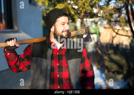 bärtige Holzfäller mit Axt im Schnee draußen Stockfoto