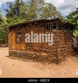 Primitive Häuschen mit Stahlblech-Dach, gebaut von lokalen Ureinwohner, ausgefertigt von Holzstäbchen und roter Erde (keine Ziegel), Uzi Island, Zanzibar, Tan Stockfoto