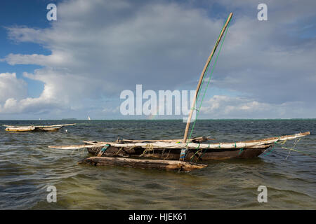 Primitive Fischer aus Holz Katamaran mit Mast auf Wasser, das von einheimischen Menschen, blauer Himmel mit Regenbogen, Matemwe, Zanzibar, Tansania, Afrika Stockfoto