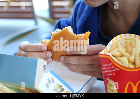 Ein Kind essen Australische McDonald's Filet-o-Fisch Burger und Pommes frites Stockfoto