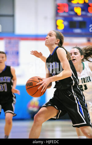 Spieler, die Montage eines Angriffs auf den Korb nach dribbling vorbei ein Verteidiger bei einem High-School-Basketball-Spiel. Stockfoto