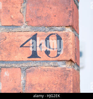 Haus Nummer 49 Zeichen auf roten Backsteinmauer schwarz lackiert Stockfoto