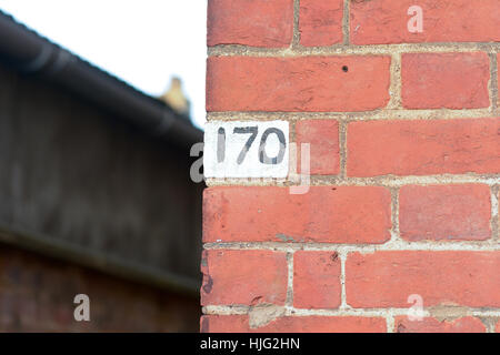 Haus Nr. 170 schwarz mit weißem Hintergrund auf roten Backsteinmauer lackiert Stockfoto