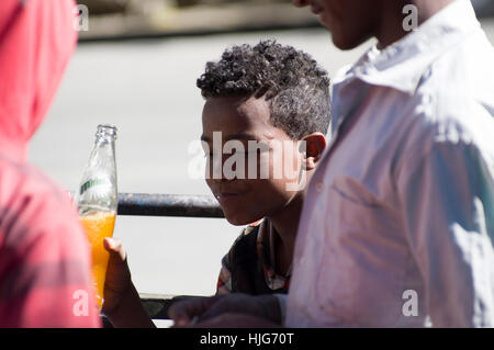 Äthiopischen jungen lächelnd mit einer orange Flasche von Miranda Stockfoto