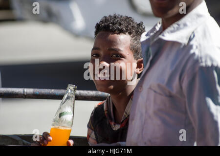 Äthiopischen jungen lächelnd mit einer orange Flasche von Miranda Stockfoto