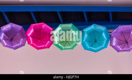 Bunte Schirme hängen an der Decke entlang der Promenade, viele Farben wie blau, gelb, rosa, grün, für vor Regen schützen Stockfoto