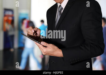 Geschäftsmann mit Tablet-Gerät auf unscharf abstrakt im Gebäude Hintergrund als Konzept arbeiten. Stockfoto