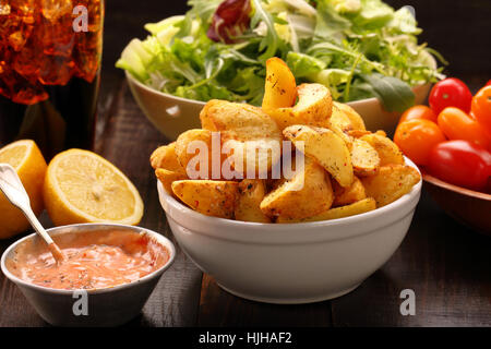 Geröstete Kartoffeln mit Dip und frischem Salat auf Holztisch Stockfoto