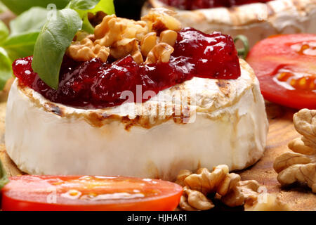 Brie Käse mit Preiselbeermarmelade und Walnüssen auf alten hölzernen Hintergrund Stockfoto