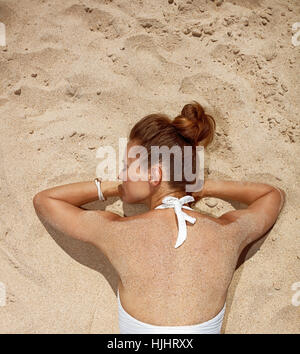 Warmen Sand Behandlung. Gesehen von hinten Frau im Badeanzug auf dem Sand verlegen Stockfoto