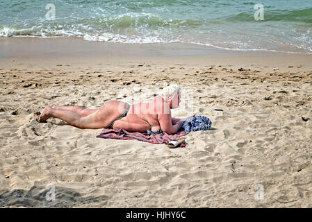 Übergewichtige Frau im Bikini und Sonnenbaden am Strand. Stockfoto