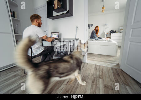 Papa arbeitet am Laptop, Mutter und Kind auf dem Bett Stockfoto