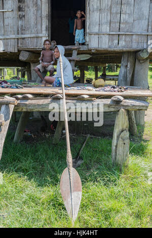 Eine junge Frau und zwei jungen auf der Veranda ihres gestelzt Hauses in einem Dorf auf dem Sepik Fluss in Papua-Neuguinea. Stockfoto