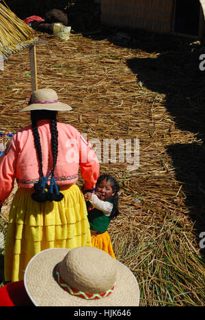 Eine Peruanische kleines Mädchen und ihre Mutter leben auf einer schwimmenden Insel im Titicacasee, Peru Stockfoto